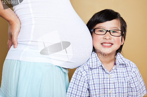Image of Asian boy listening to her pregnant mom belly