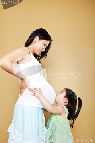 Image of Girl kissing pregnant mother