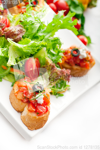 Image of original Italian fresh bruschetta served with fresh salad and ve