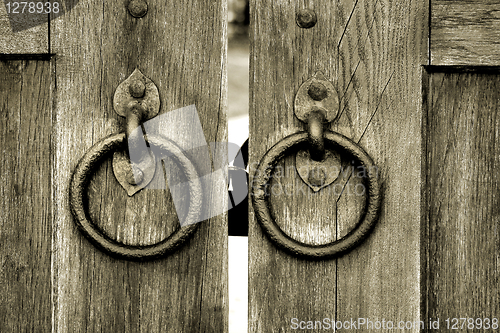 Image of ancient wooden gate with door knocker rings