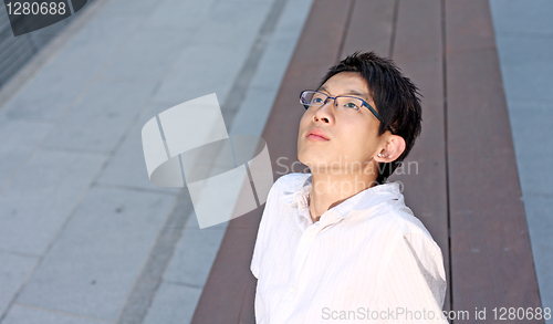 Image of Young caucasian businessman sitting on bench