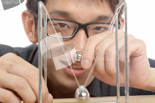 Image of man moving Newton balls in office 