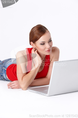 Image of Cute female lying down and using a laptop