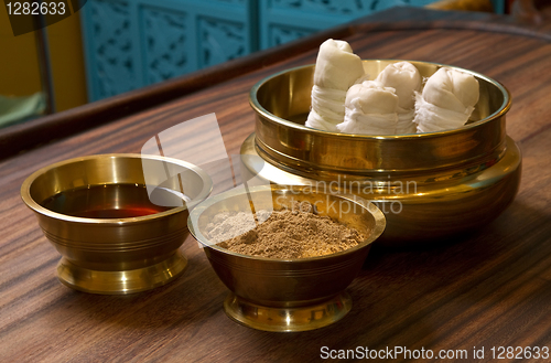 Image of herbs powder and oil in bronze cups