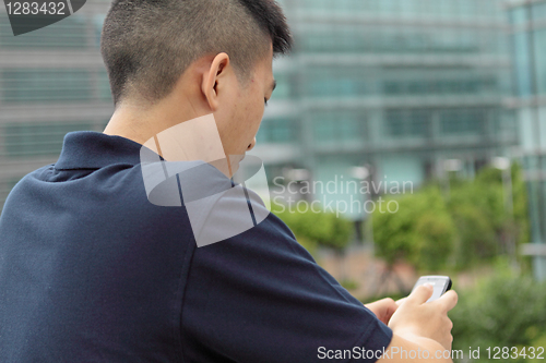 Image of Asian man typing a message on mobile phone.