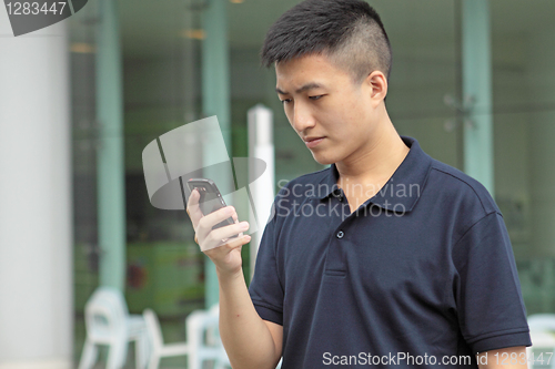 Image of Asian man typing a message on mobile phone.