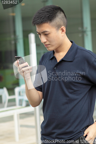 Image of Asian man typing a message on mobile phone.