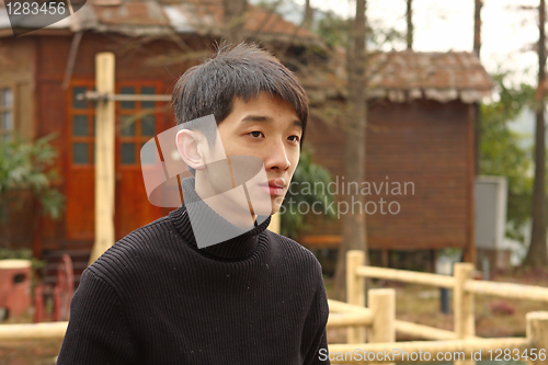 Image of Asian man stand against a old house 