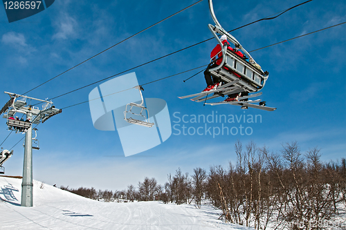 Image of Chair lift with skiers on a blue sky