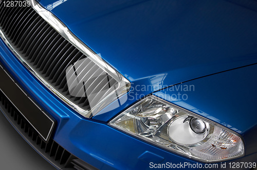 Image of headlight and grate of radiator on a dark blue car