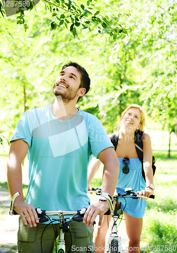 Image of Young happy couple riding a bicycle