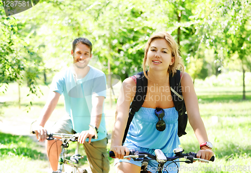 Image of Young happy couple riding a bicycle