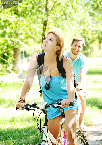 Image of Young happy couple riding a bicycle