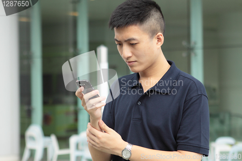 Image of Asian man typing a message on mobile phone.