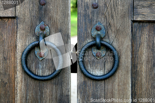 Image of ancient wooden gate with door knocker rings