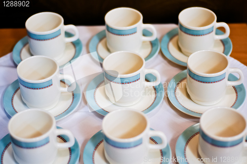 Image of nine white porcelain tea cups and saucers and napkins