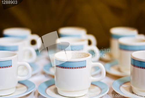 Image of nine white porcelain tea cups and saucers and napkins