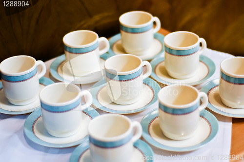 Image of nine white porcelain tea cups and saucers and napkins