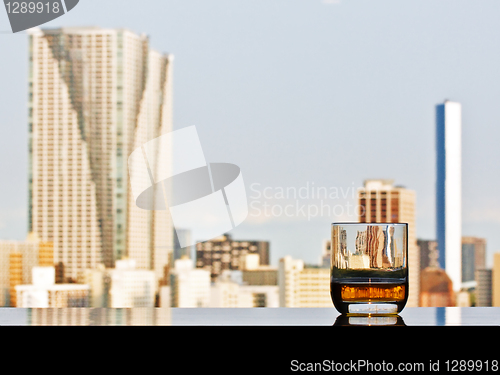 Image of A glass of whisky with panoramic city view