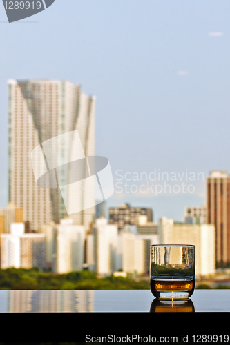 Image of A glass of whisky with city view on background