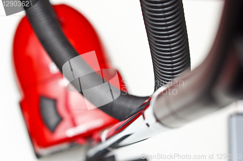 Image of The red vacuum cleaner with a black hose on a white background
