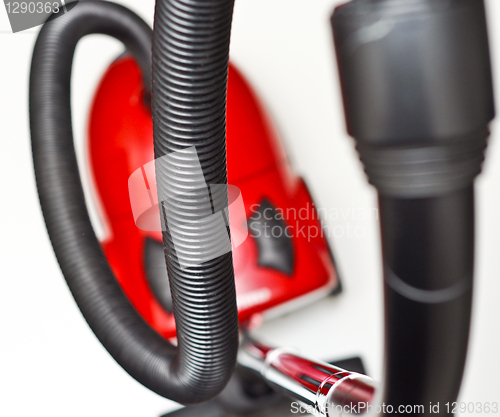 Image of The red vacuum cleaner with a black hose on a white background
