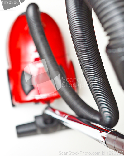 Image of The red vacuum cleaner with a black hose on a white background
