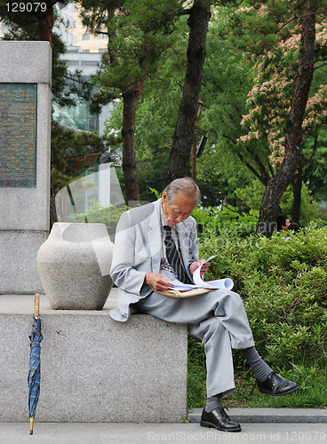 Image of Old Korean man reading at Tapol Park, Seoul, South Korea