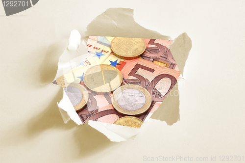 Image of euro money behind hole in paper