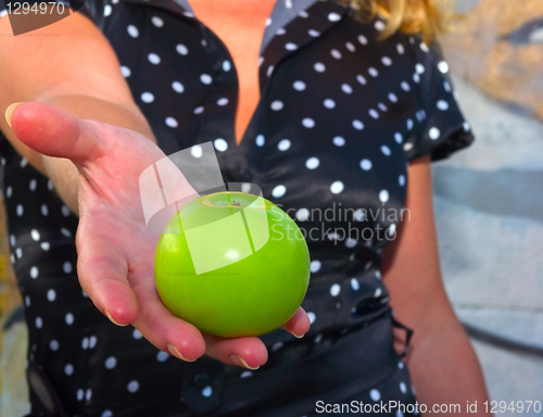 Image of beautiful young woman holds out a green apple