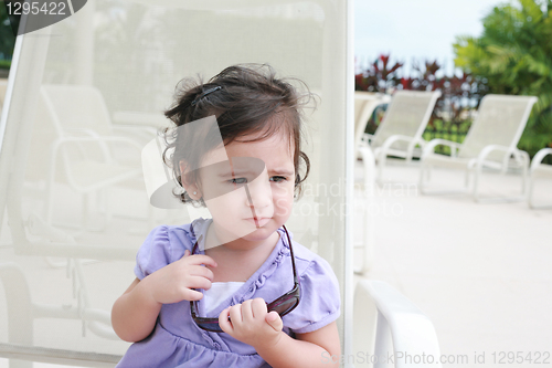 Image of cute toddler girl in summer clothes and sunglasses lyiing on a l