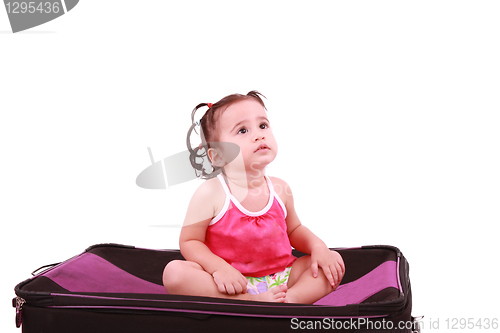 Image of cute little girl sitting on the black suitcase 