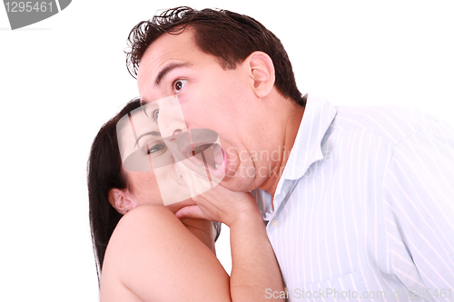 Image of Woman tells something into surprised guy's ear isolated on white