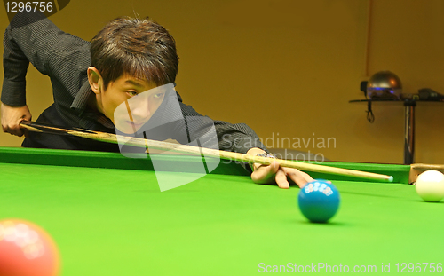 Image of Young man concentrating while aiming at pool ball while playing 