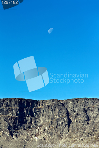 Image of Moon on a background of blue sky and mountains