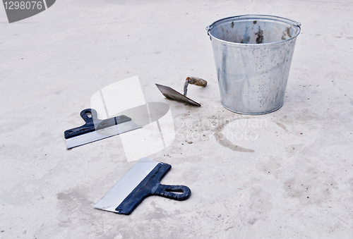 Image of metal bucket with cement and spatulas