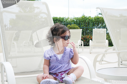 Image of adorable young baby girl wearing sunglasses in flirting position