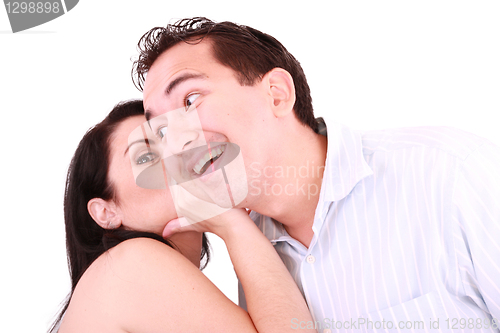 Image of pretty girl talking secret to young man in his ear, man smiling 