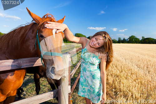 Image of horse and blond girl in paddock on summers
