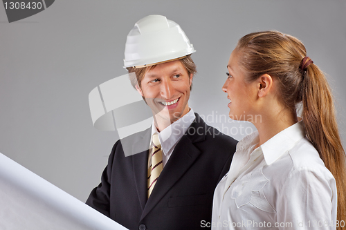 Image of An architect wearing a hard hat and co-worker
