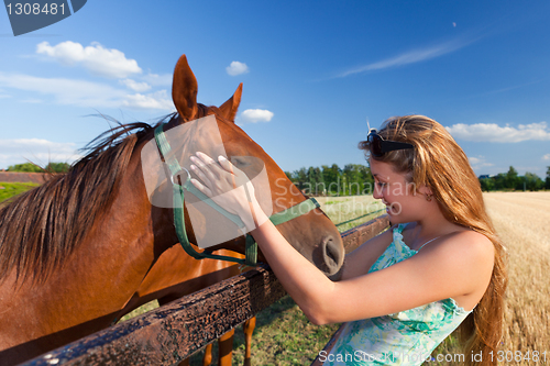 Image of horse and blond girl in paddock on summers