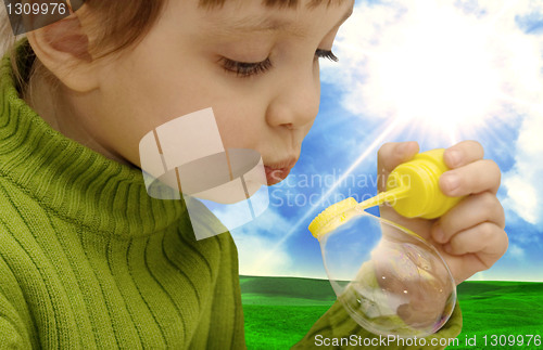 Image of The girl inflating soap bubbles on a meadow