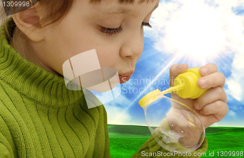 Image of The girl inflating soap bubbles on a meadow