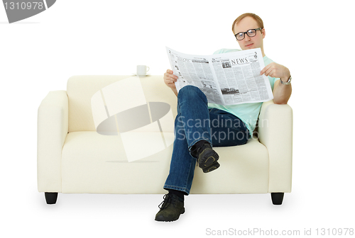 Image of Man reading newspaper at home on sofa