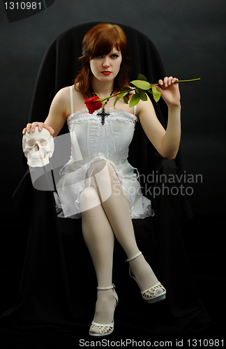 Image of Girl sits in black chair with a rose and skull