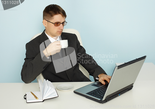 Image of Businessman reads news online and drinking coffee