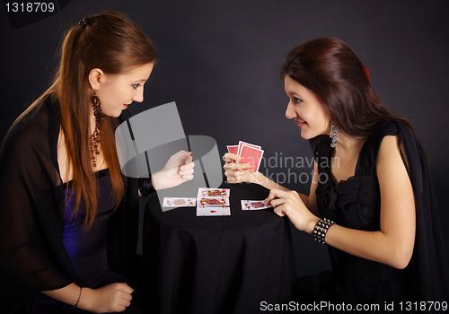 Image of Two girls friends engaged in fortune-telling cards