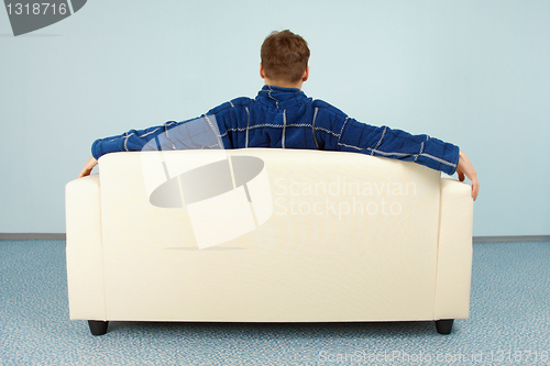 Image of Young man sitting at home on couch