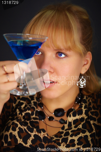 Image of Young woman looks at glass with unusual cocktail