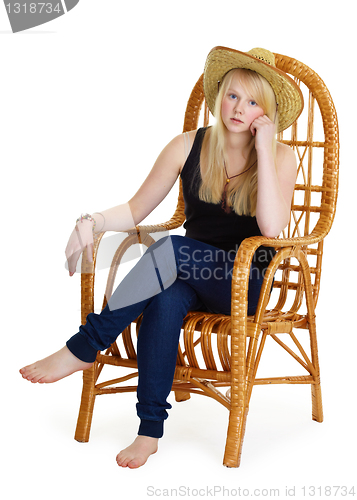 Image of dreamy girl is sitting in a wicker chair
